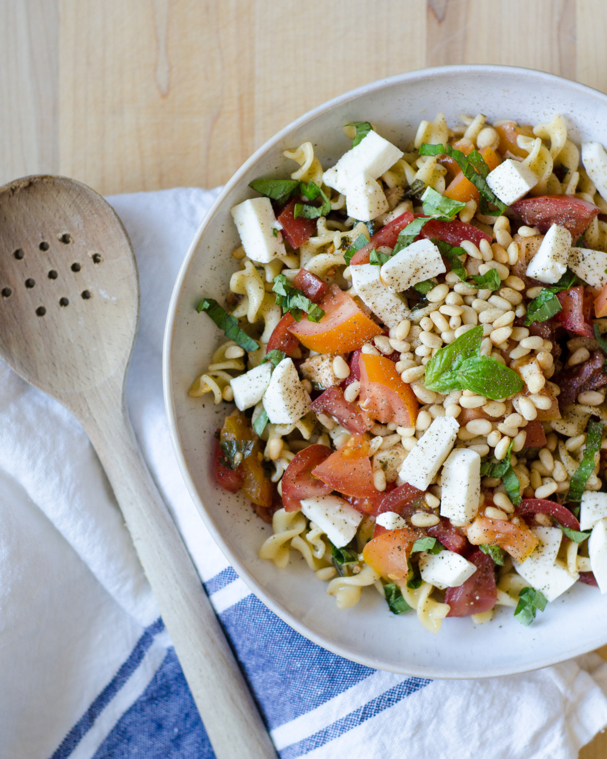 A quick and delicious recipe for caprese pasta with tomatoes, fresh mozzarella, basil, and pine nuts. A crowd pleaser that's ready in under 30 minutes!