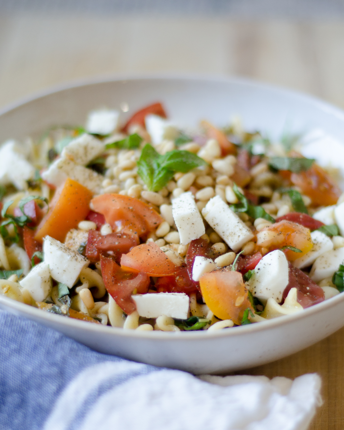 A quick and delicious recipe for caprese pasta with tomatoes, fresh mozzarella, basil, and pine nuts. A crowd pleaser that's ready in under 30 minutes!