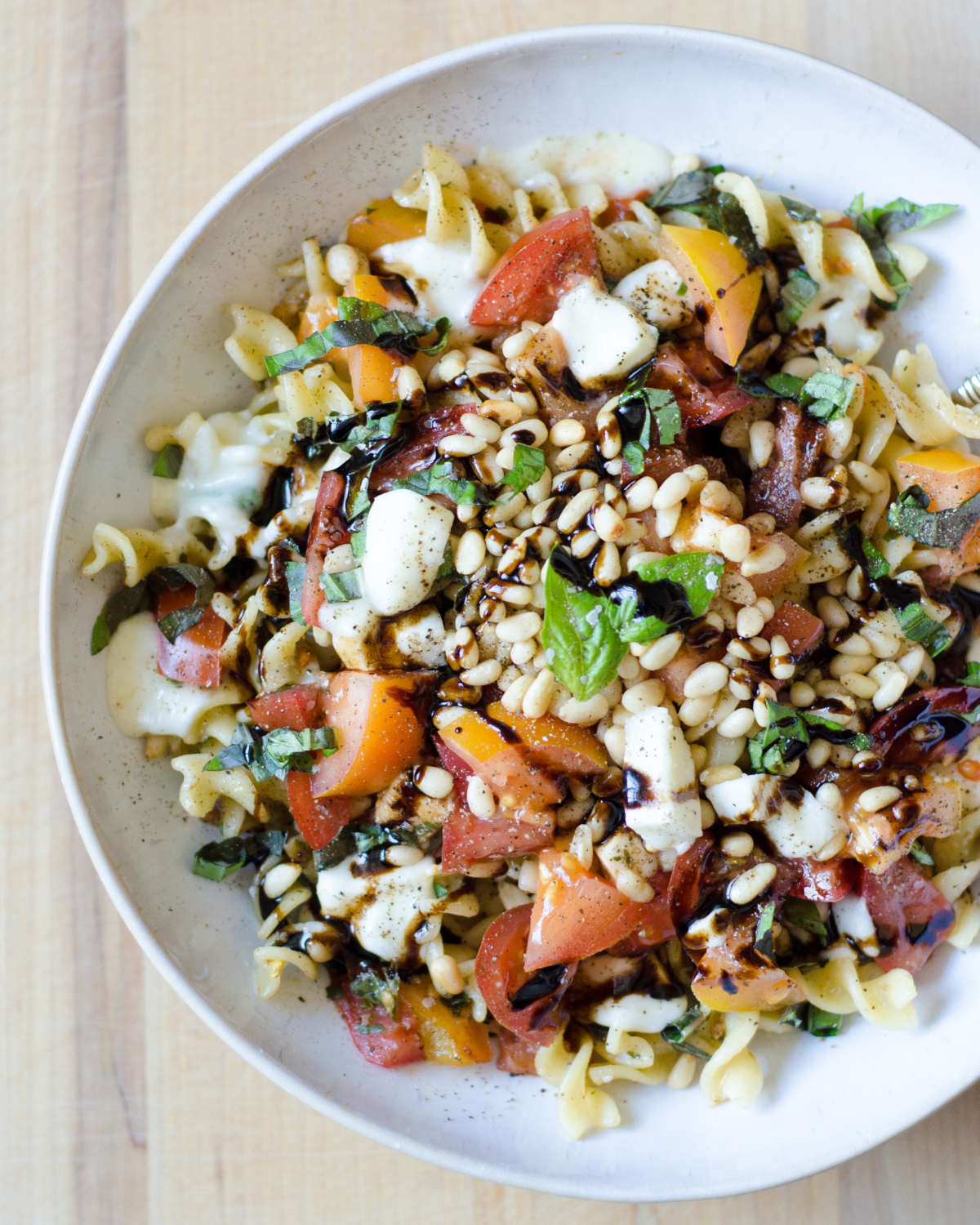 A quick and delicious recipe for caprese pasta with tomatoes, fresh mozzarella, basil, and pine nuts. A crowd pleaser that's ready in under 30 minutes!