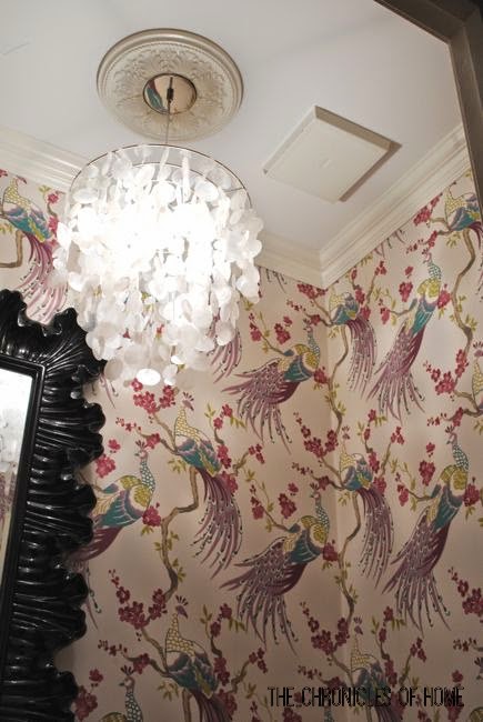 Makeover a powder room on a budget with simple upgrades - bold peacock wallpaper, wainscoting, and a glam light fixture.