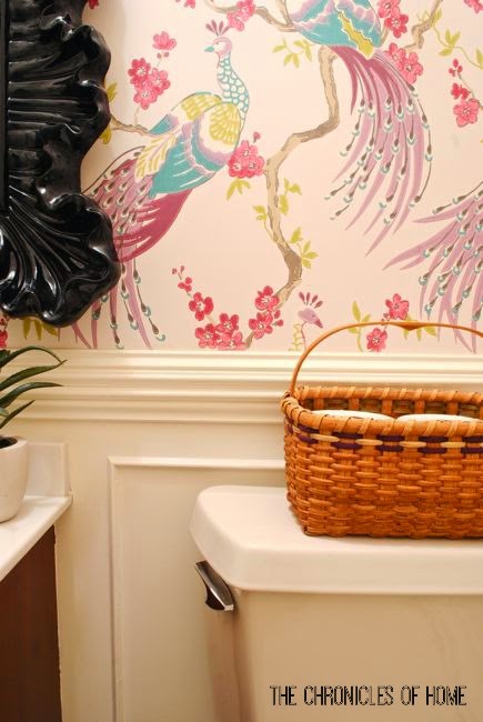 Makeover a powder room on a budget with simple upgrades - bold peacock wallpaper, wainscoting, and a glam light fixture.