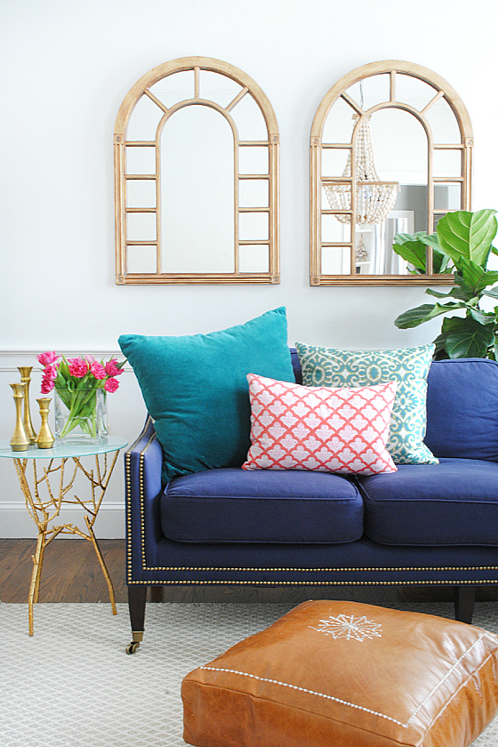 living room with navy sofa, colorful pillows for spring, and a DIY leather pouf