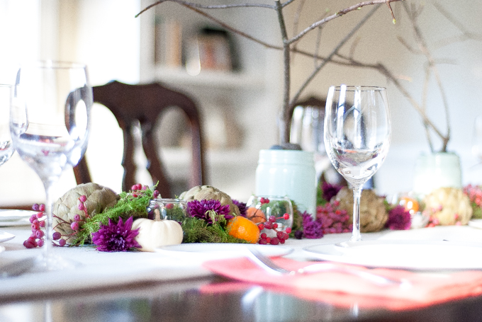 A jewel toned Thanksgiving tablescape with moss, artichokes, clementines, mums, and bare branches. Fresh, chic, and dramatic but still so simple to assemble!