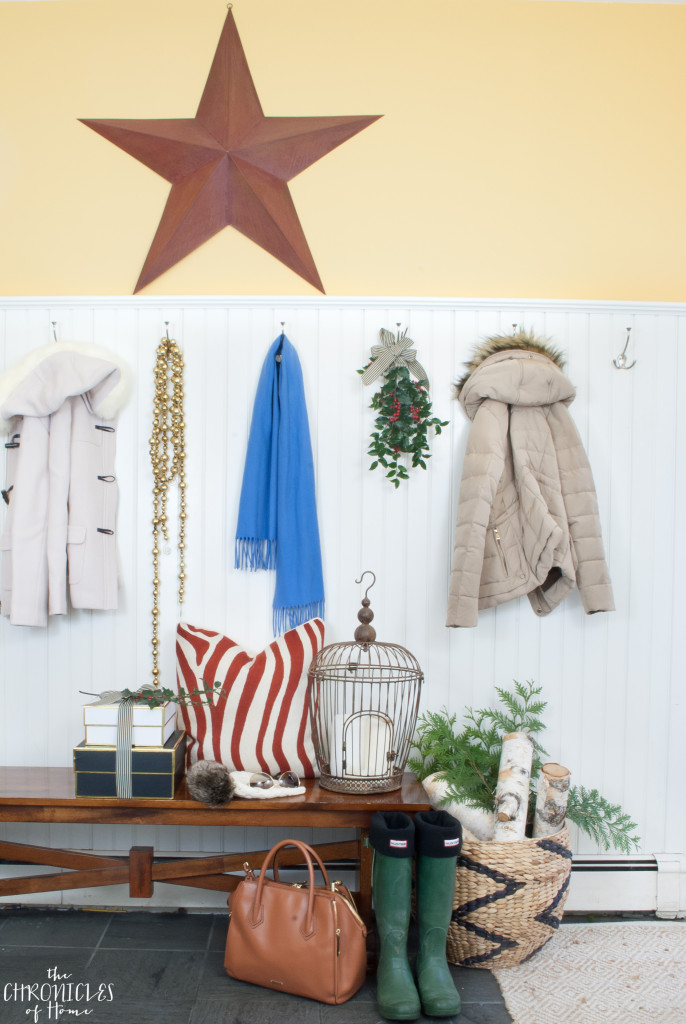 A Christmas mudroom with red barn star, greenery, and firewood