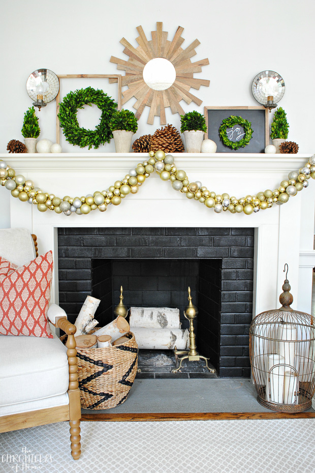 Christmas mantle with boxwood, pinecones, natural wood, and gold ornaments. Classic, natural, and glam.