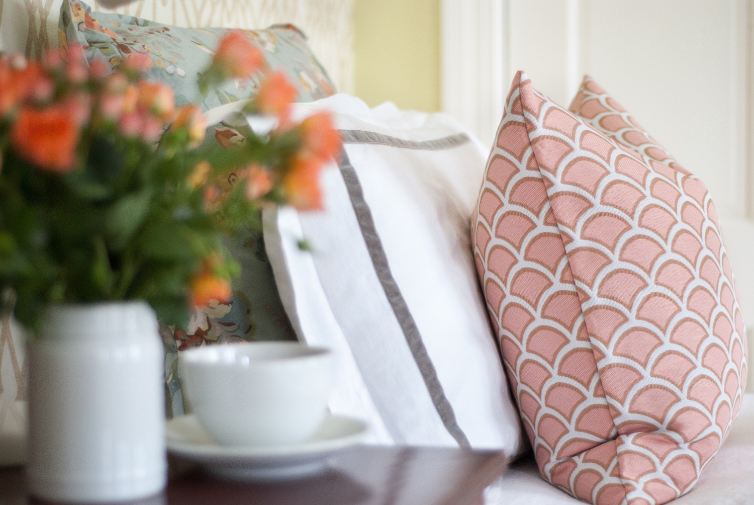 Classic bedroom with white duvet, soft graphic wallpaper, dusty blue and blush accents.