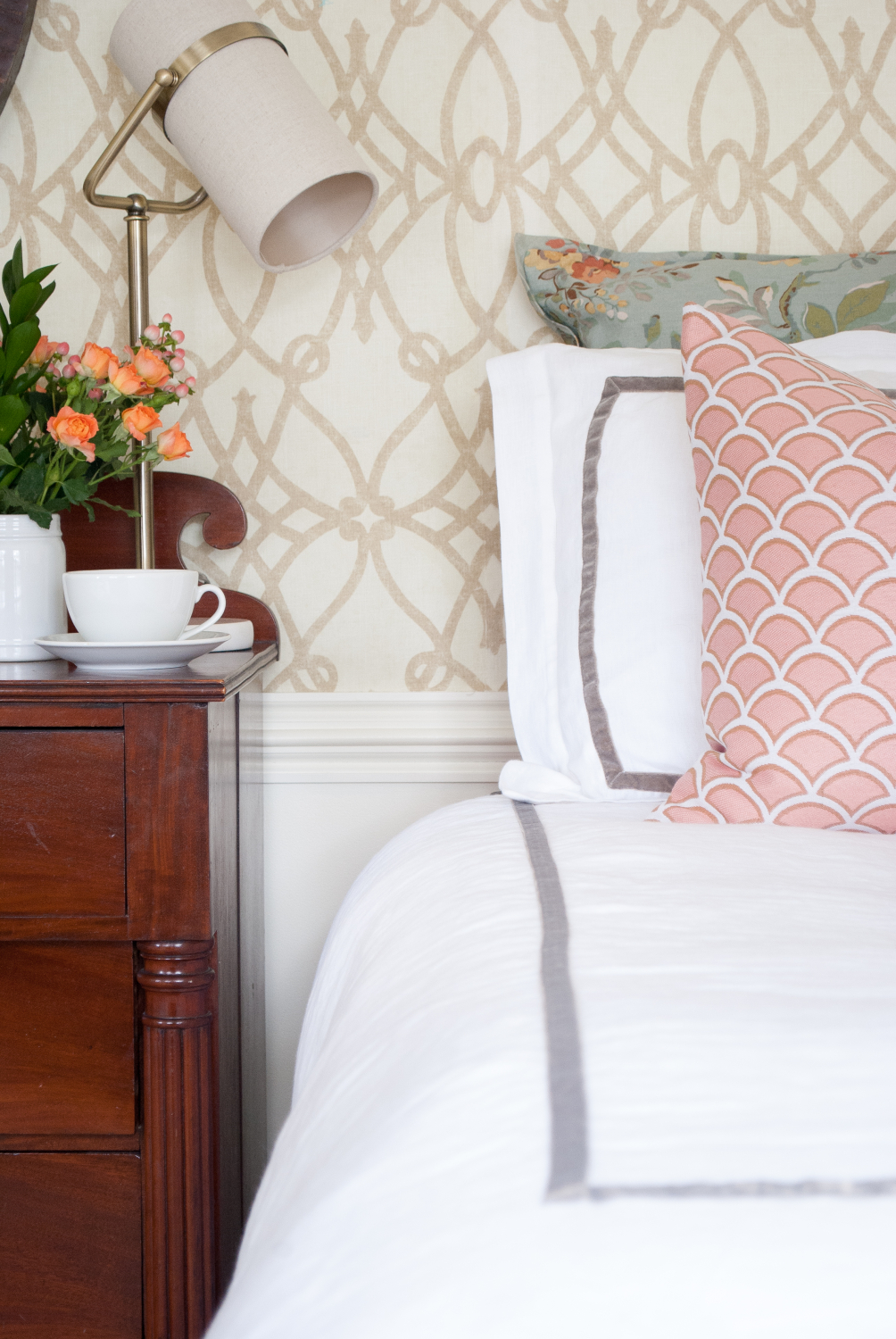 Classic bedroom with white duvet, soft graphic wallpaper, dusty blue and blush accents.