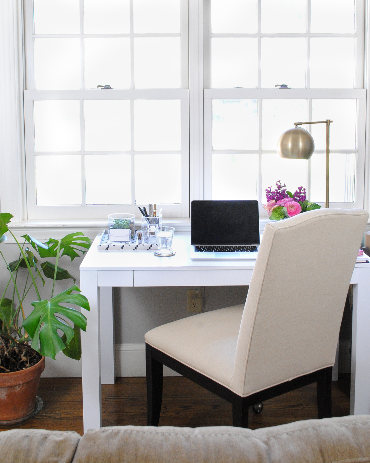 Pretty desk nook with white parsons desk, brass task lamp, lucite and gold accessories