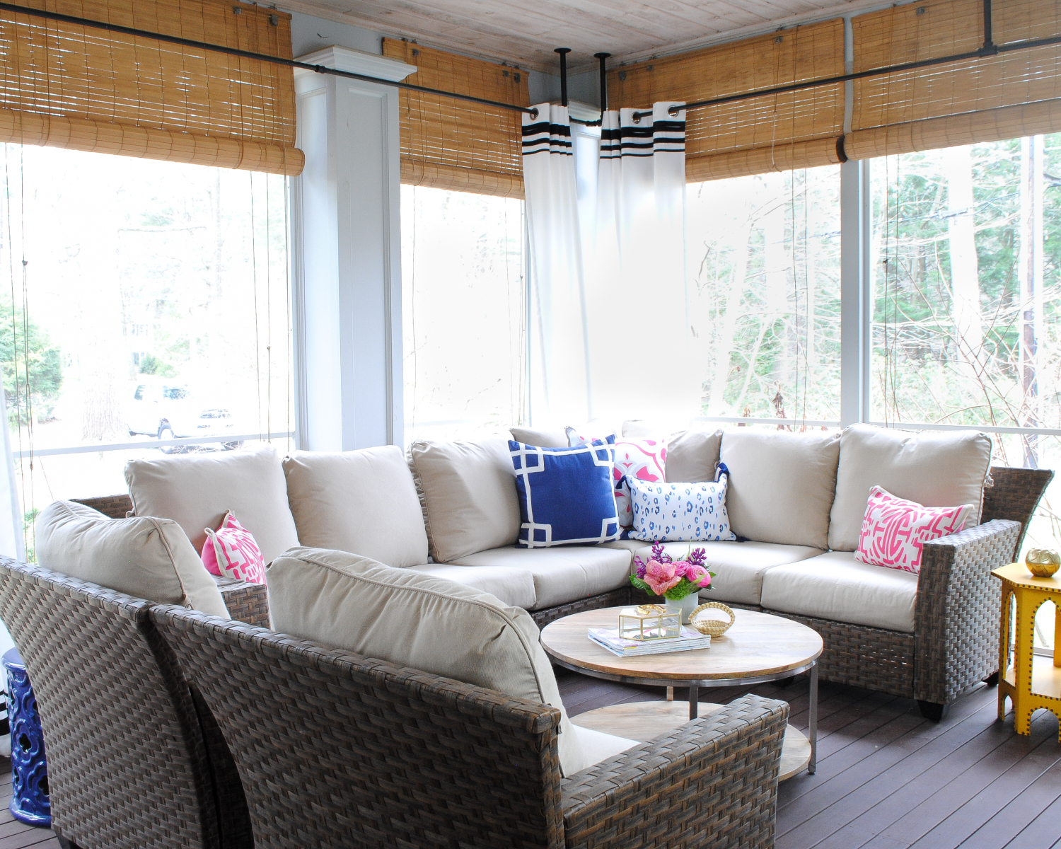 Screened porch with woven wicker, round coffee table, navy blue and pink accents - classic with a touch of contemporary!