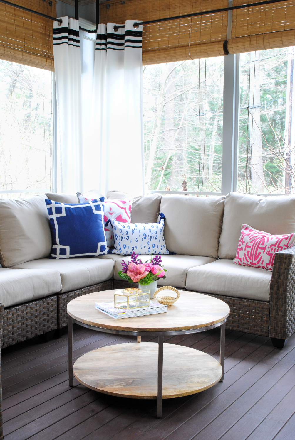 Screened porch with woven wicker, round coffee table, navy blue and pink accents - classic with a touch of contemporary!