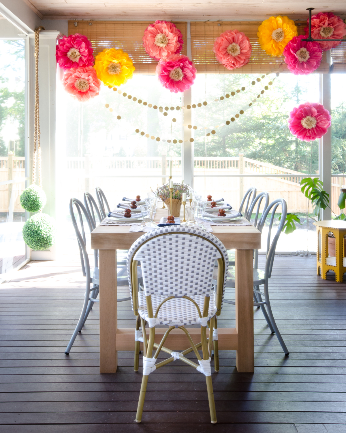 Fall outdoor dinner party with paper flowers, gold circle garlands, and a simple table with mini pumpkins, brass candlesticks, and miniature flower pots.