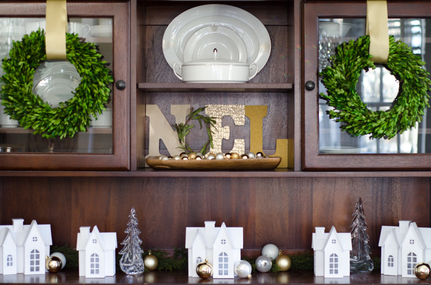 Christmas dining room with boxwood wreaths, Noel display, and a Christmas village scene