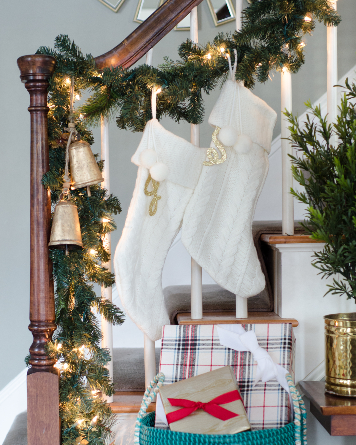 Classic Christmas entryway with greenery, twinkle lights, cable knit stockings, and more! So much inspiration!!