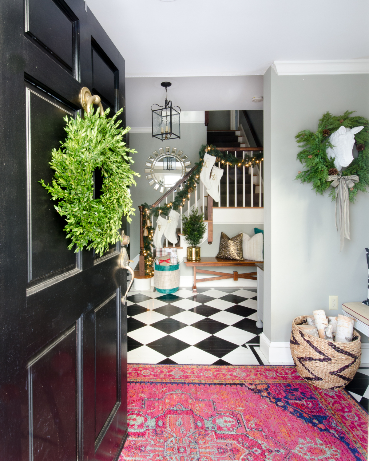 Classic Christmas entryway with greenery, twinkle lights, cable knit stockings, and more! So much inspiration!!