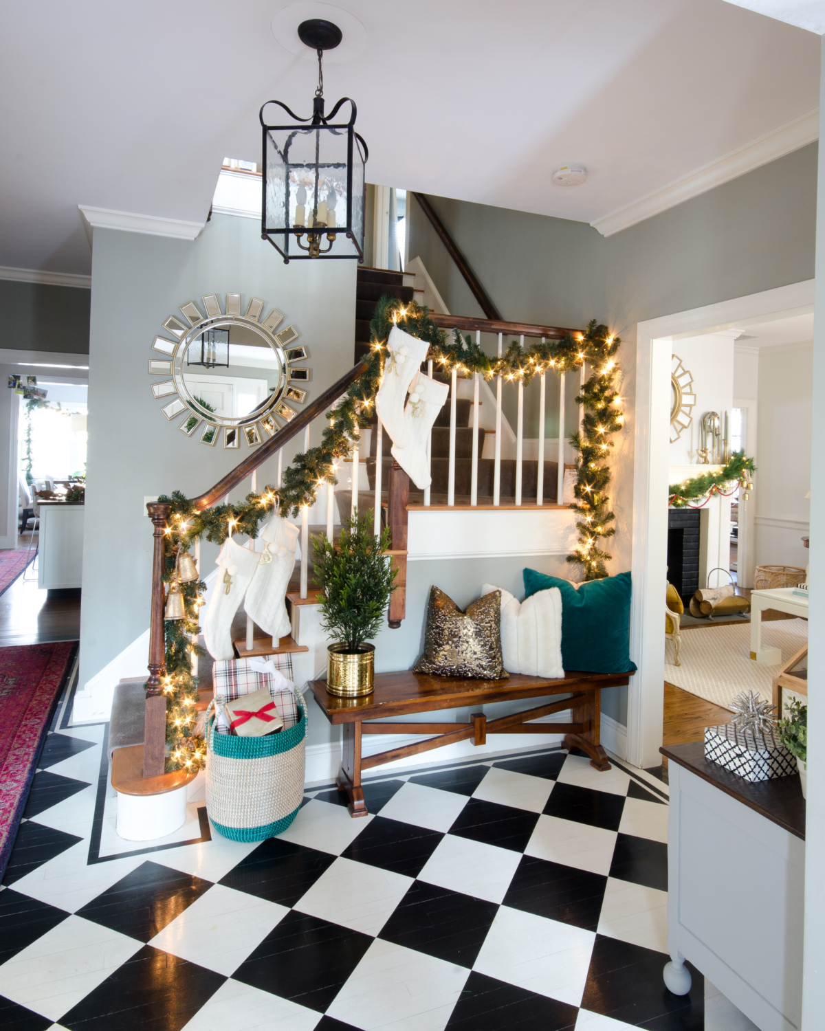 Classic Christmas entryway with greenery, twinkle lights, cable knit stockings, and more! So much inspiration!!