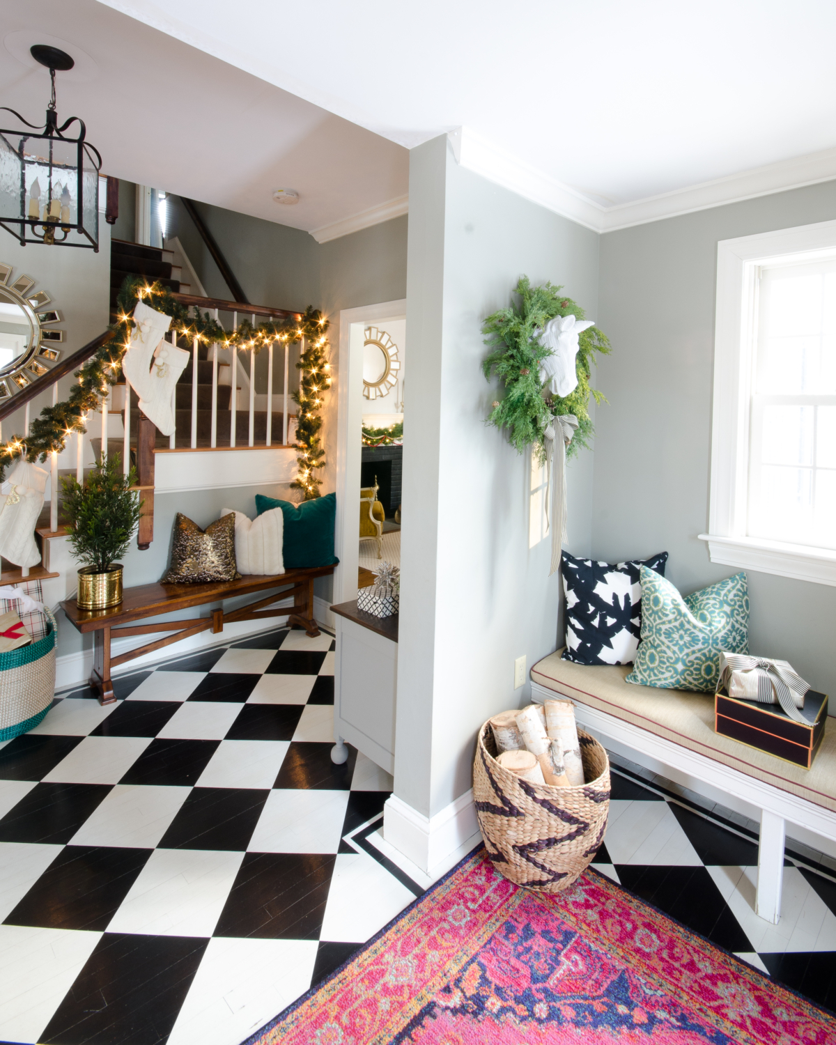 Classic Christmas entryway with greenery, twinkle lights, cable knit stockings, and more! So much inspiration!!