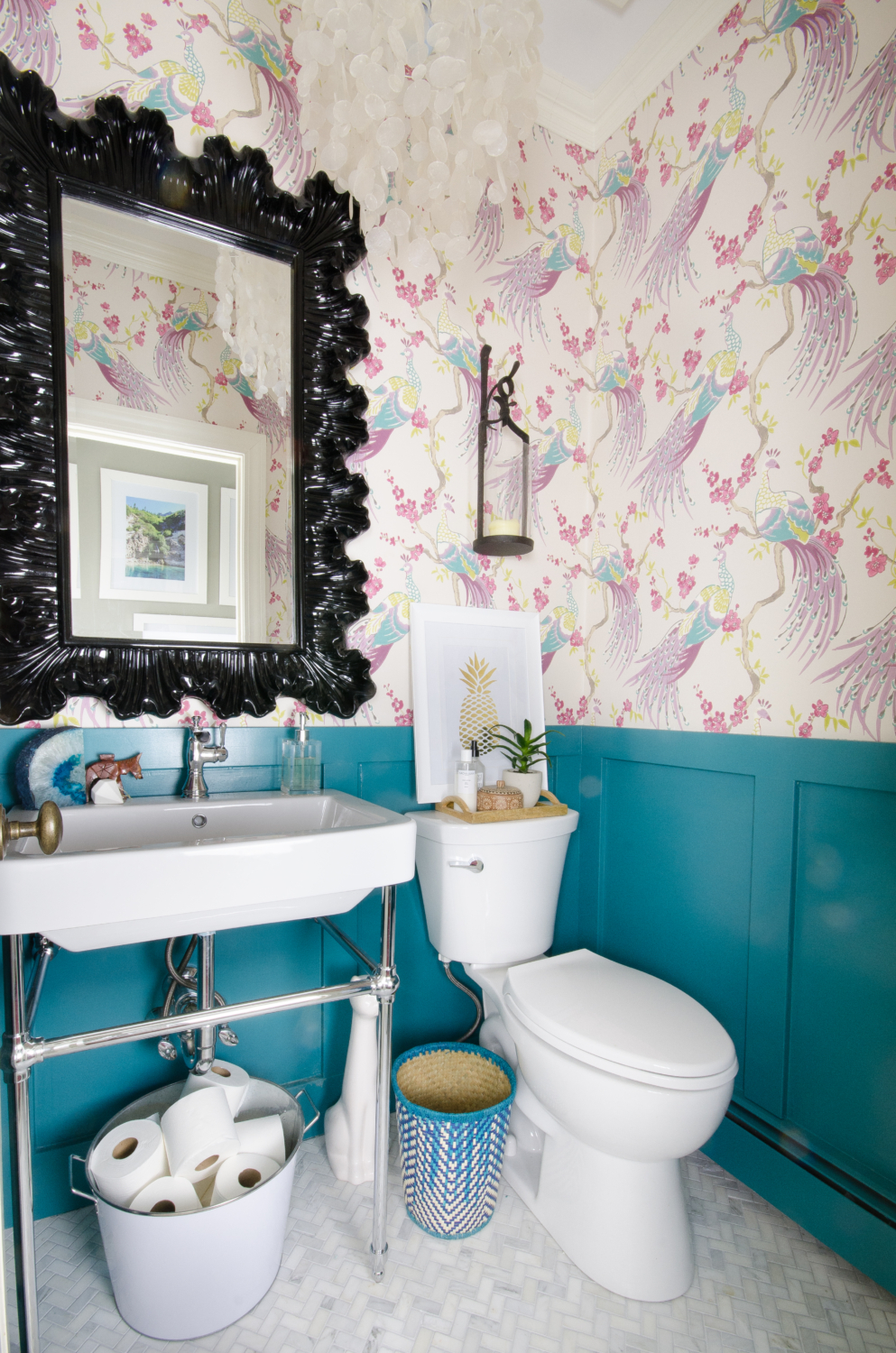 A small powder room gets a majorly gorgeous makeover, including marble tile, teal wainscoting, console sink, bird wallpaper, and capiz shell pendant. You won't believe this before and after!