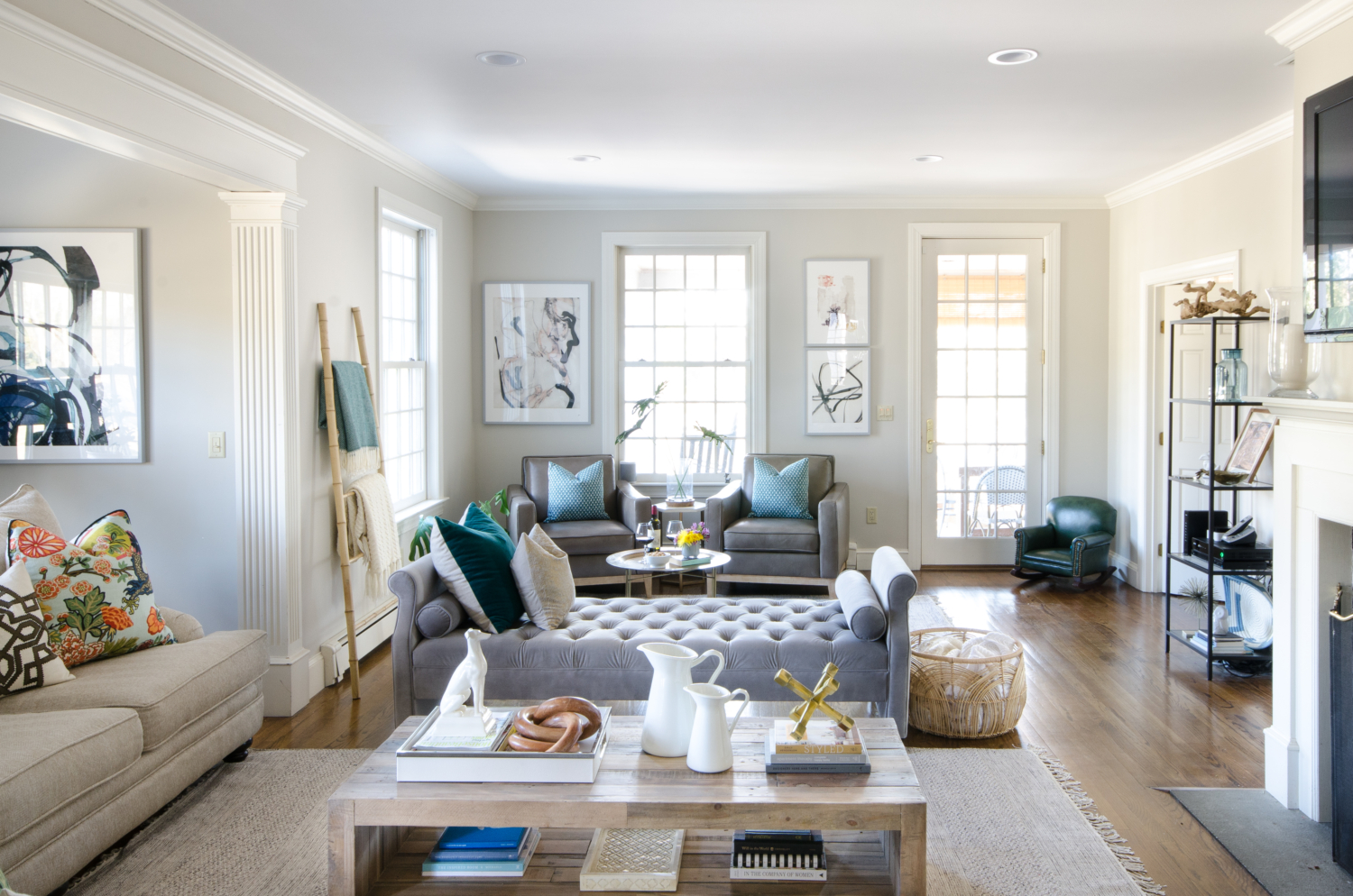 A stylish family room that's both chic and family-friendly featuring neutral furniture and thoughtful pops of color. Features an oversized English roll arm sofa, a tufted daybed / backless sofa that divides the room into two seating areas, and reclaimed wood accent tables to balance traditional and rustic.