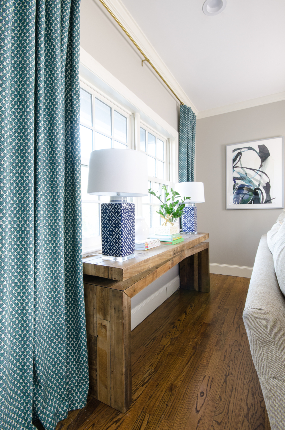 A stylish family room that's both chic and family-friendly featuring neutral furniture and thoughtful pops of color. Features an oversized English roll arm sofa, a tufted daybed / backless sofa that divides the room into two seating areas, and reclaimed wood accent tables to balance traditional and rustic.