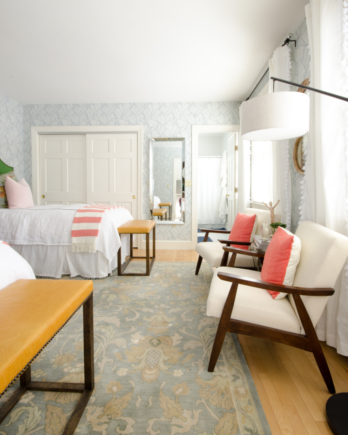 Gorgeous guest room with palm wallpaper, green linen headboards, mustard yellow leather benches, and accents of blush and coral