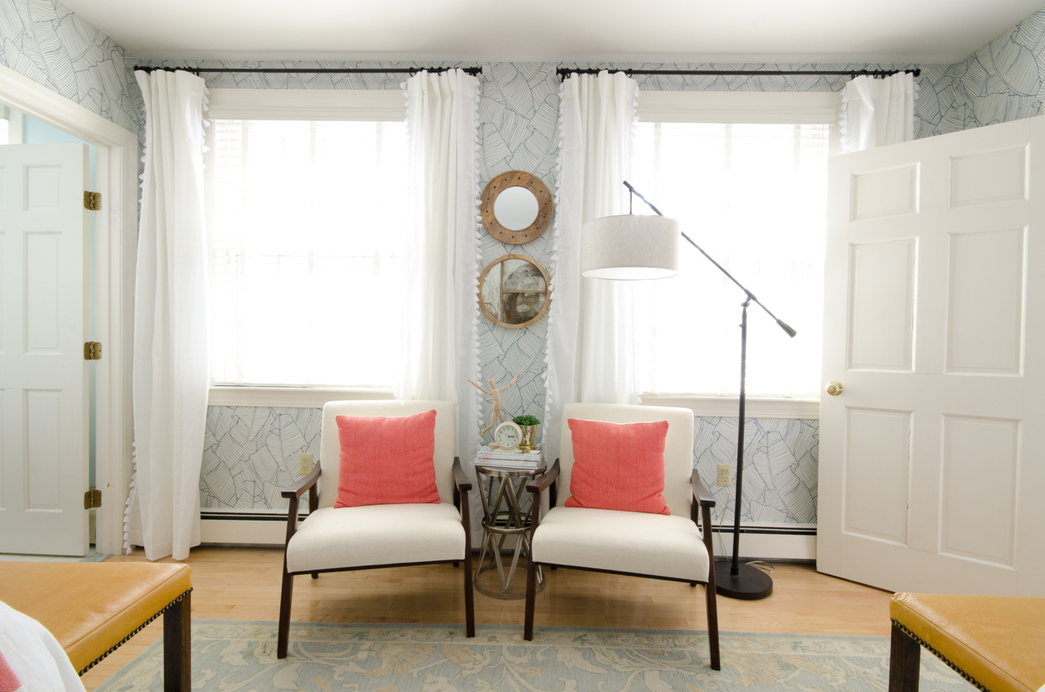 Gorgeous guest room with palm wallpaper, green linen headboards, mustard yellow leather benches, and accents of blush and coral