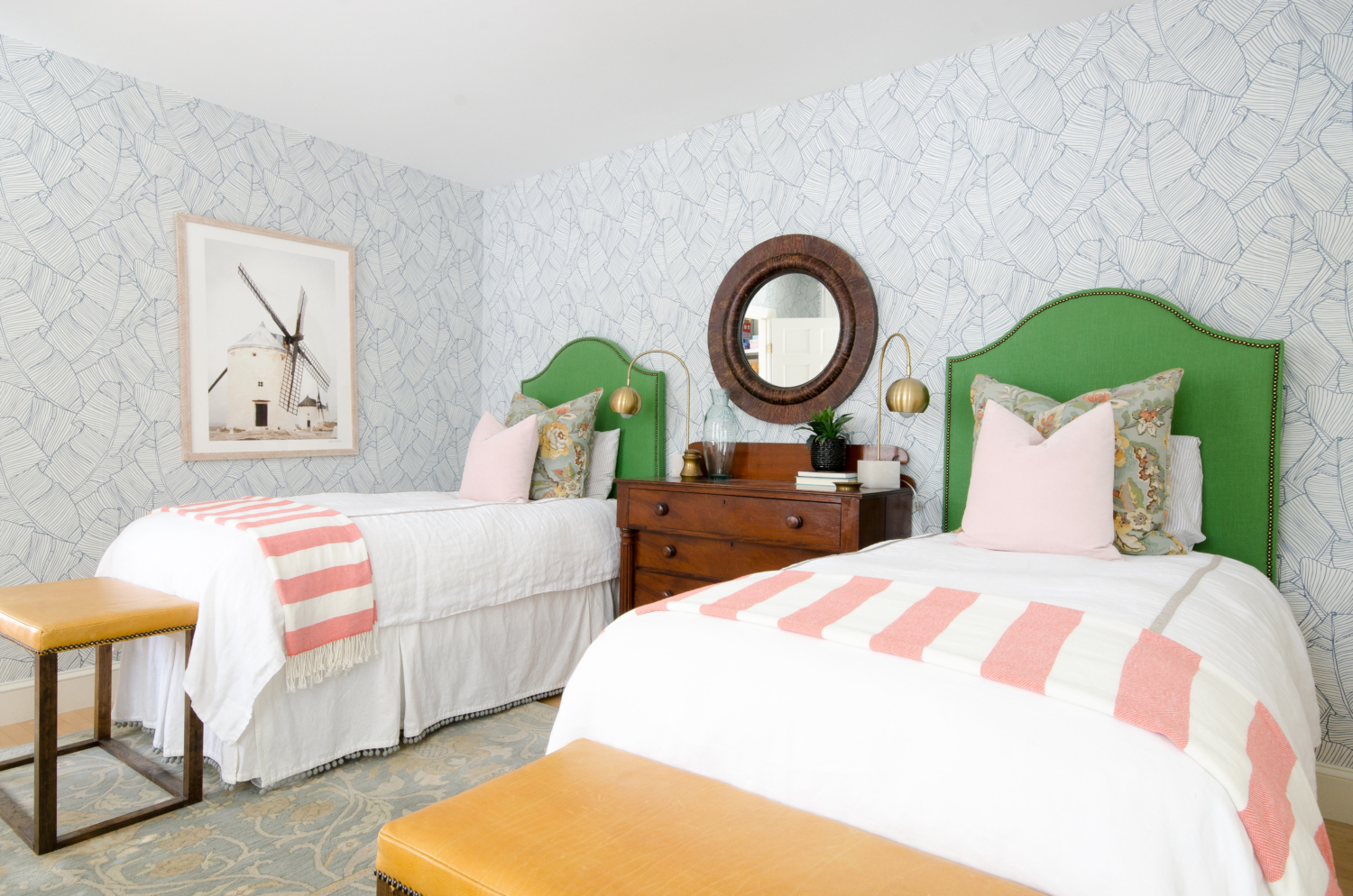 Gorgeous guest room with palm wallpaper, green linen headboards, mustard yellow leather benches, and accents of blush and coral