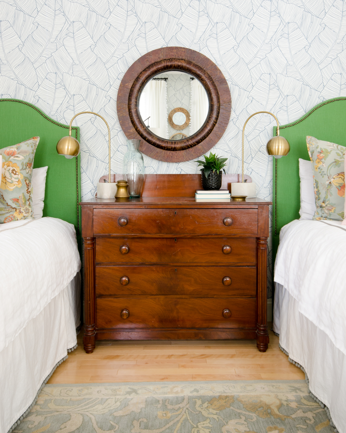 Gorgeous guest room with palm wallpaper, green linen headboards, mustard yellow leather benches, and accents of blush and coral