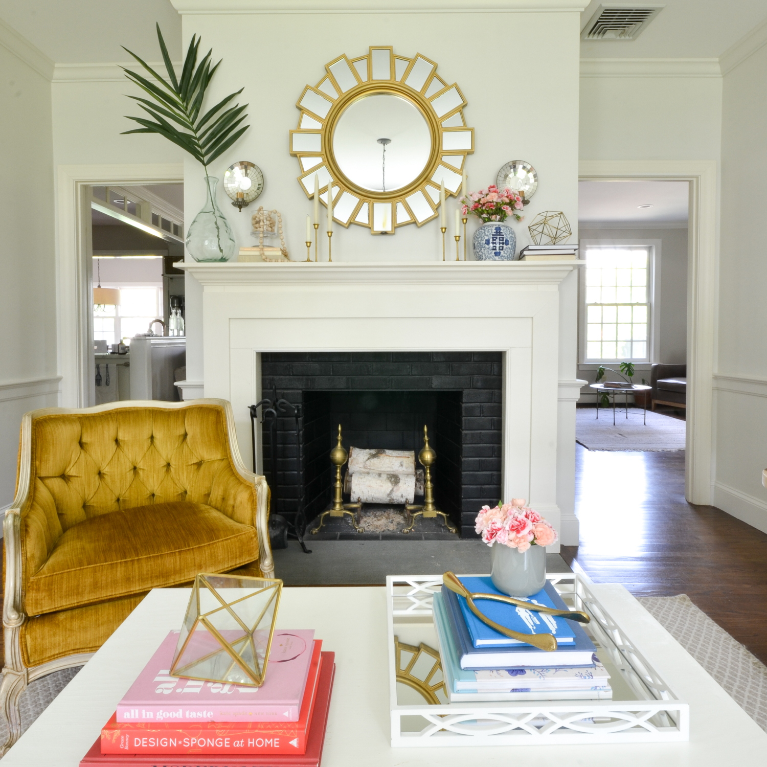 Living room with a neutral base, gold, navy blue, coral. Juju hat feather wall hanging is a striking centerpiece.