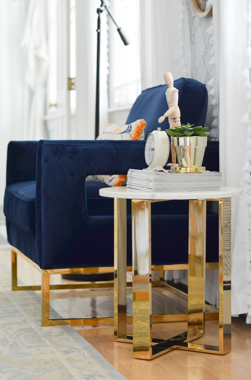 Navy blue velvet chair with brass and marble side table