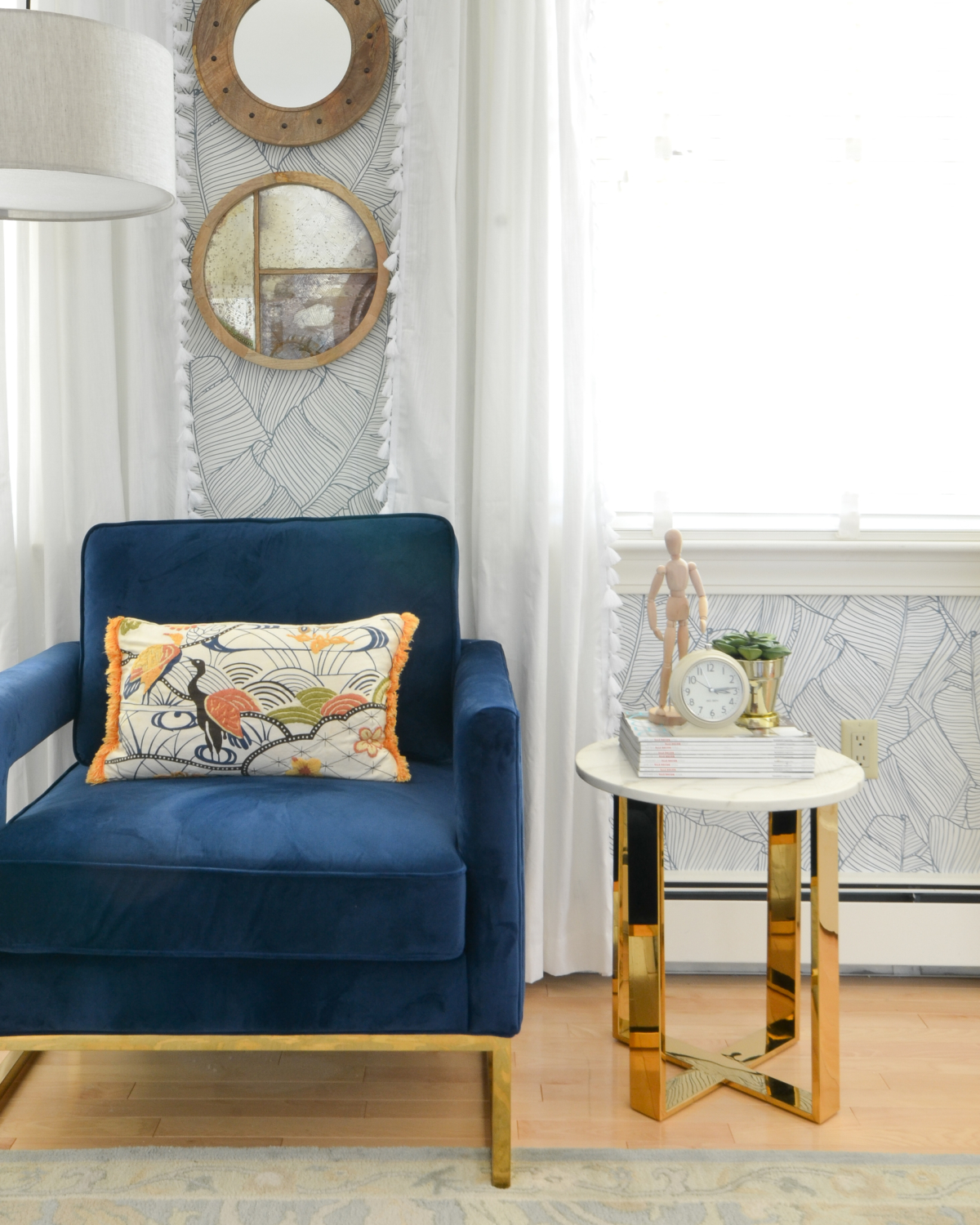 Wallpapered bedroom with twin beds, green upholstered headboards, navy blue, brass, and coral accents