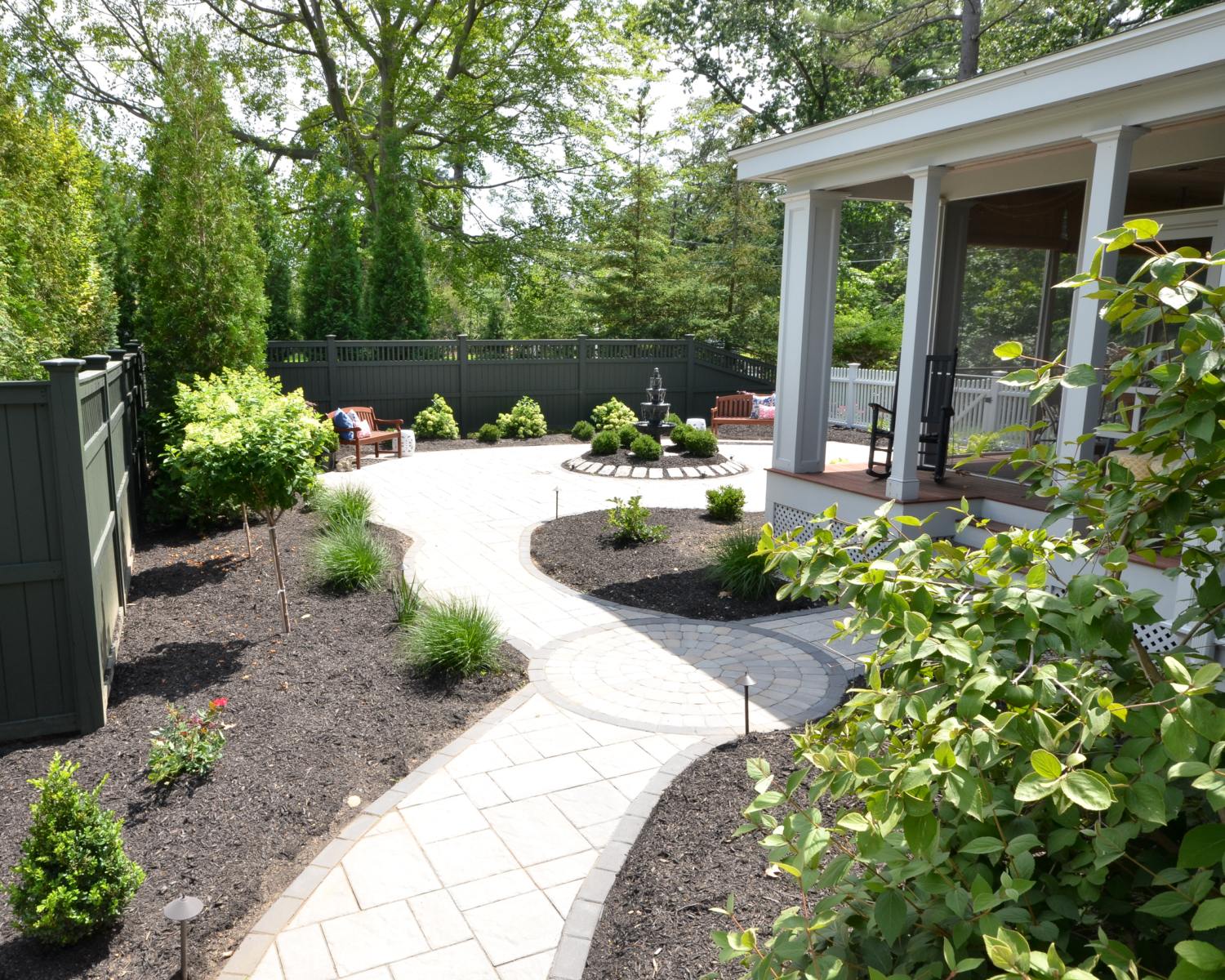 Amazing backyard landscaping makeover that includes a Trex deck, a paver patio with gas firepit, and a paver patio with a fountain and benches. So much outdoor inspiration!