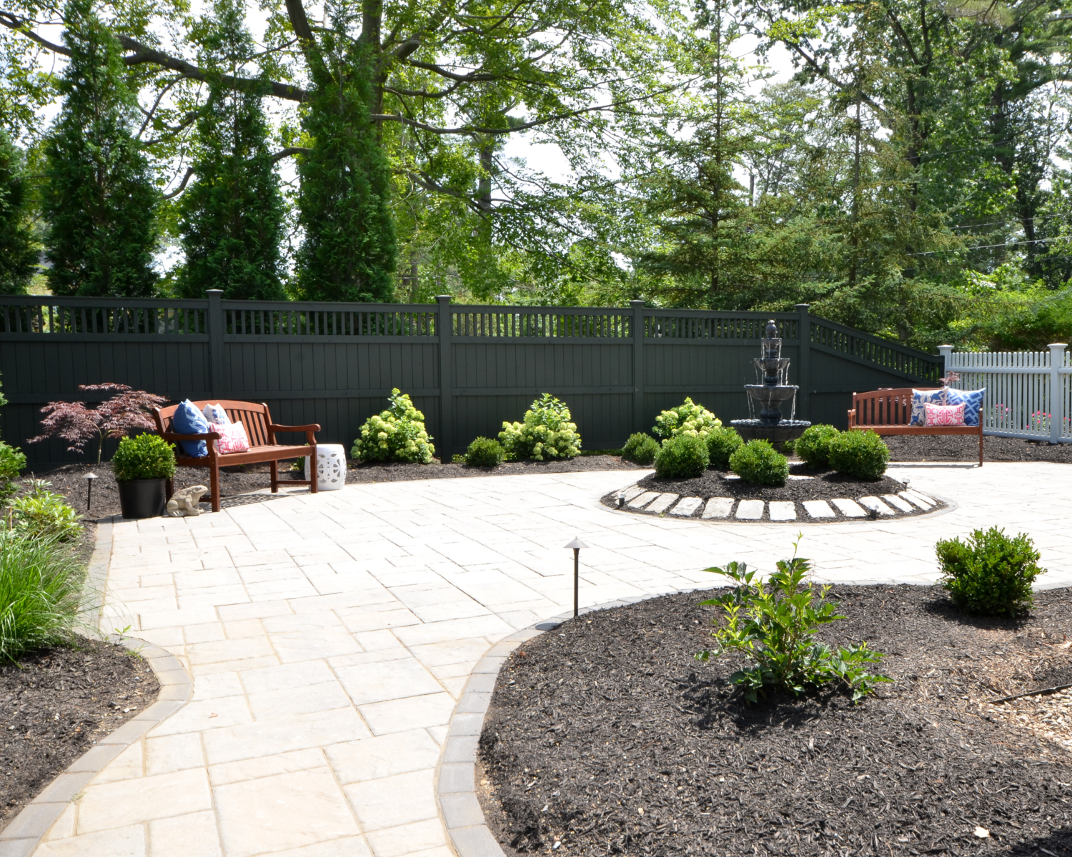 Amazing backyard landscaping makeover that includes a Trex deck, a paver patio with gas firepit, and a paver patio with a fountain and benches. So much outdoor inspiration!