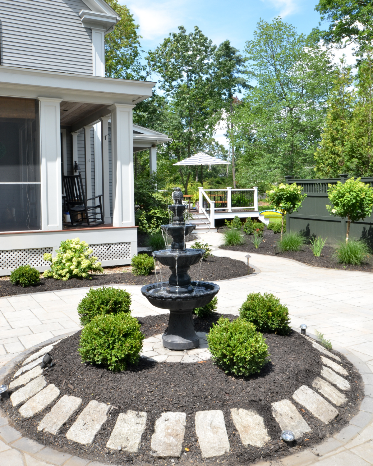 Amazing backyard landscaping makeover that includes a Trex deck, a paver patio with gas firepit, and a paver patio with a fountain and benches. So much outdoor inspiration!