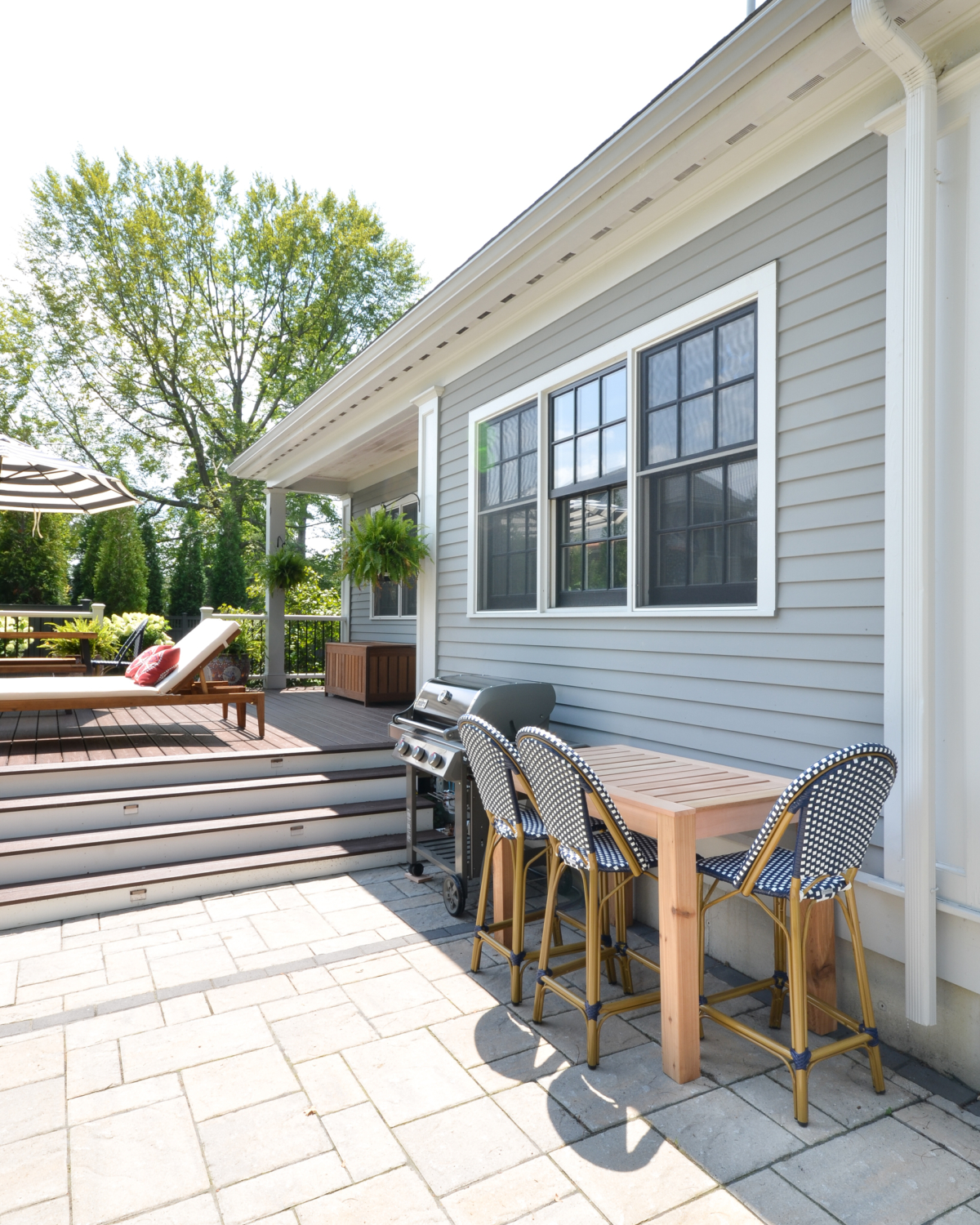 Amazing backyard landscaping makeover that includes a Trex deck, a paver patio with gas firepit, and a paver patio with a fountain and benches. So much outdoor inspiration!