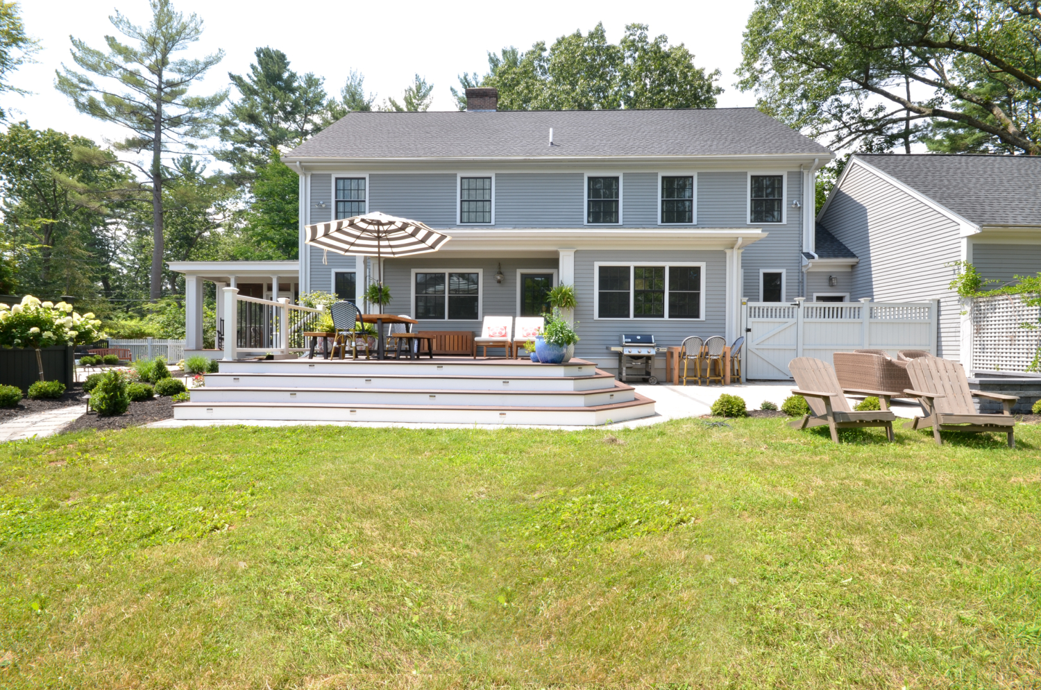 Amazing backyard landscaping makeover that includes a Trex deck, a paver patio with gas firepit, and a paver patio with a fountain and benches. So much outdoor inspiration!