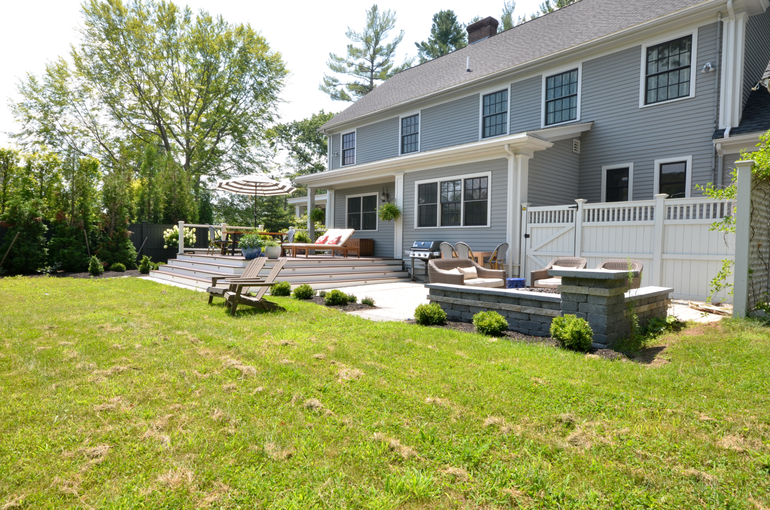 Amazing backyard landscaping makeover that includes a Trex deck, a paver patio with gas firepit, and a paver patio with a fountain and benches. So much outdoor inspiration!