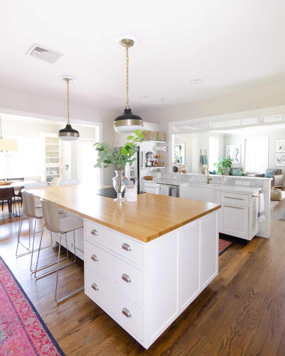 Classic white kitchen with butcher block counter and pendants similar to the Hicks pendant but way more affordable! Transom windows divide the kitchen and family room. Perimeter counter is quartzite that looks like marble!