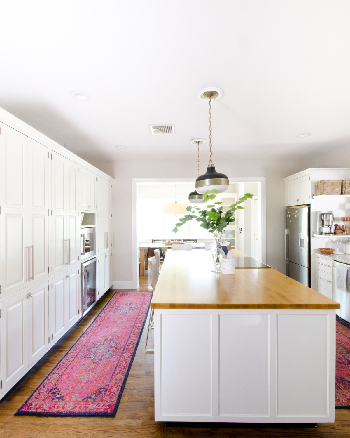 Classic white kitchen with butcher block counter and pendants similar to the Hicks pendant but way more affordable! Transom windows divide the kitchen and family room. Perimeter counter is quartzite that looks like marble!