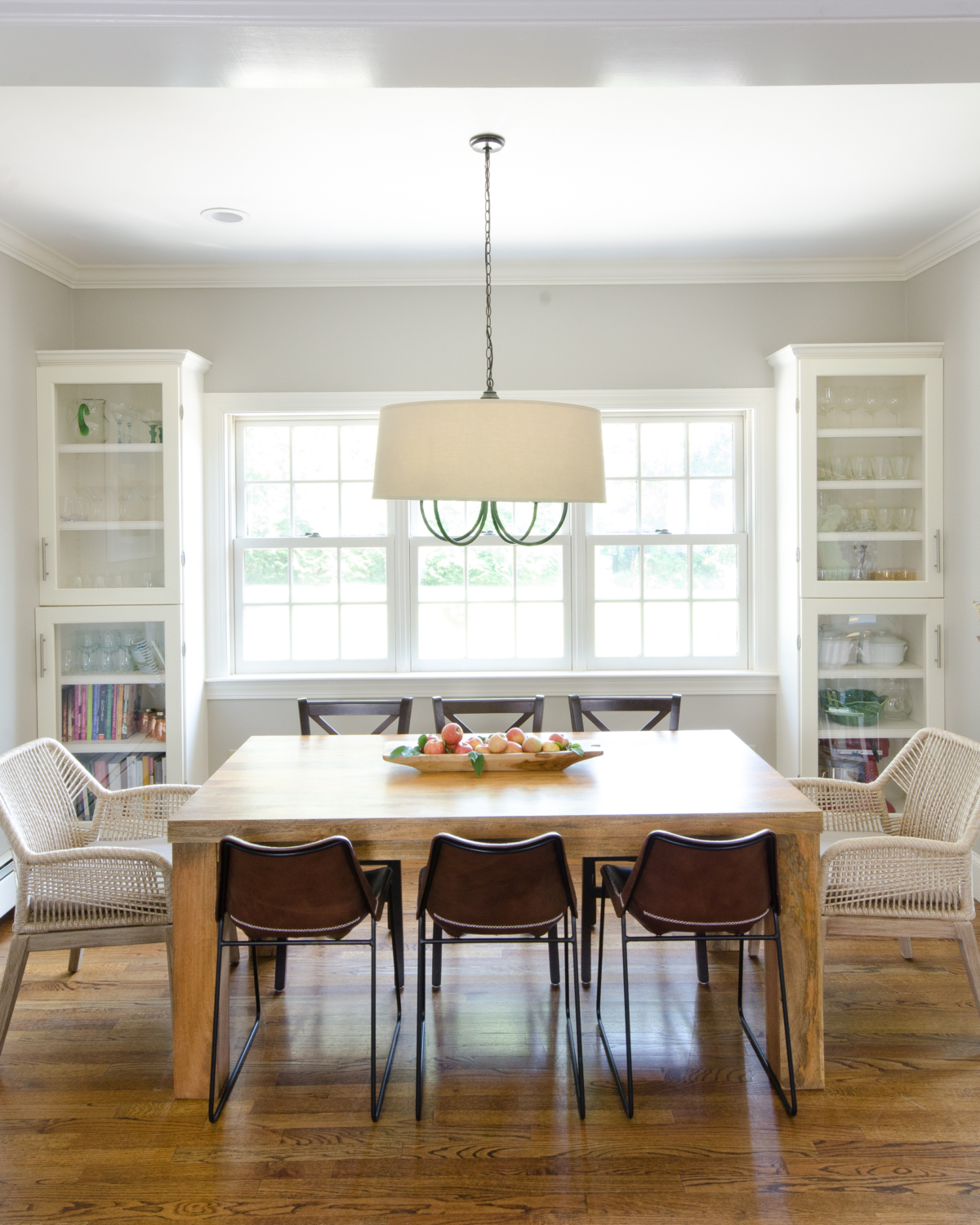 Pretty, neutral breakfast nook with farmhouse table, rope armchairs, and leather side chairs