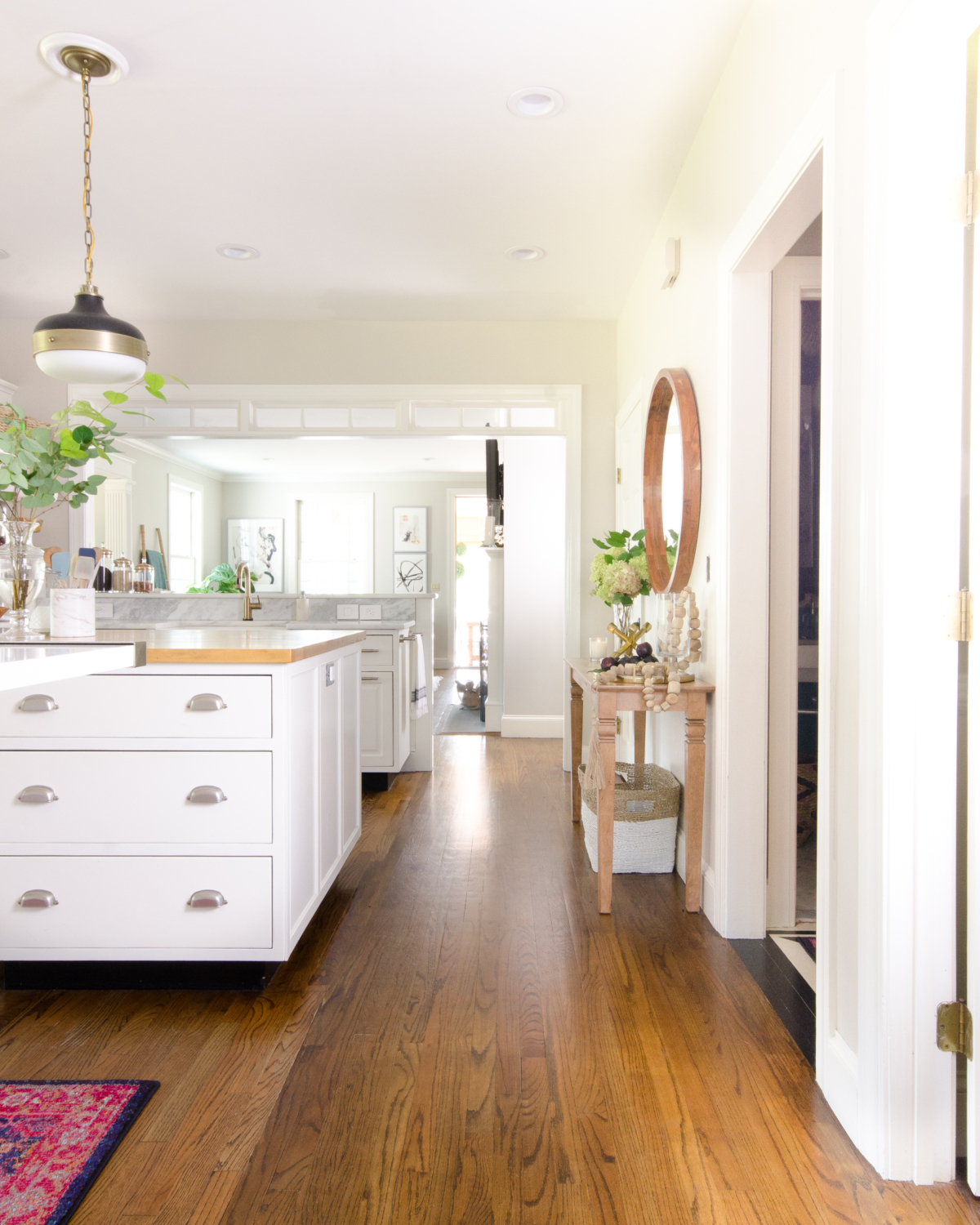 Classic white kitchen with butcher block counter and pendants similar to the Hicks pendant but way more affordable! Transom windows divide the kitchen and family room. Perimeter counter is quartzite that looks like marble!