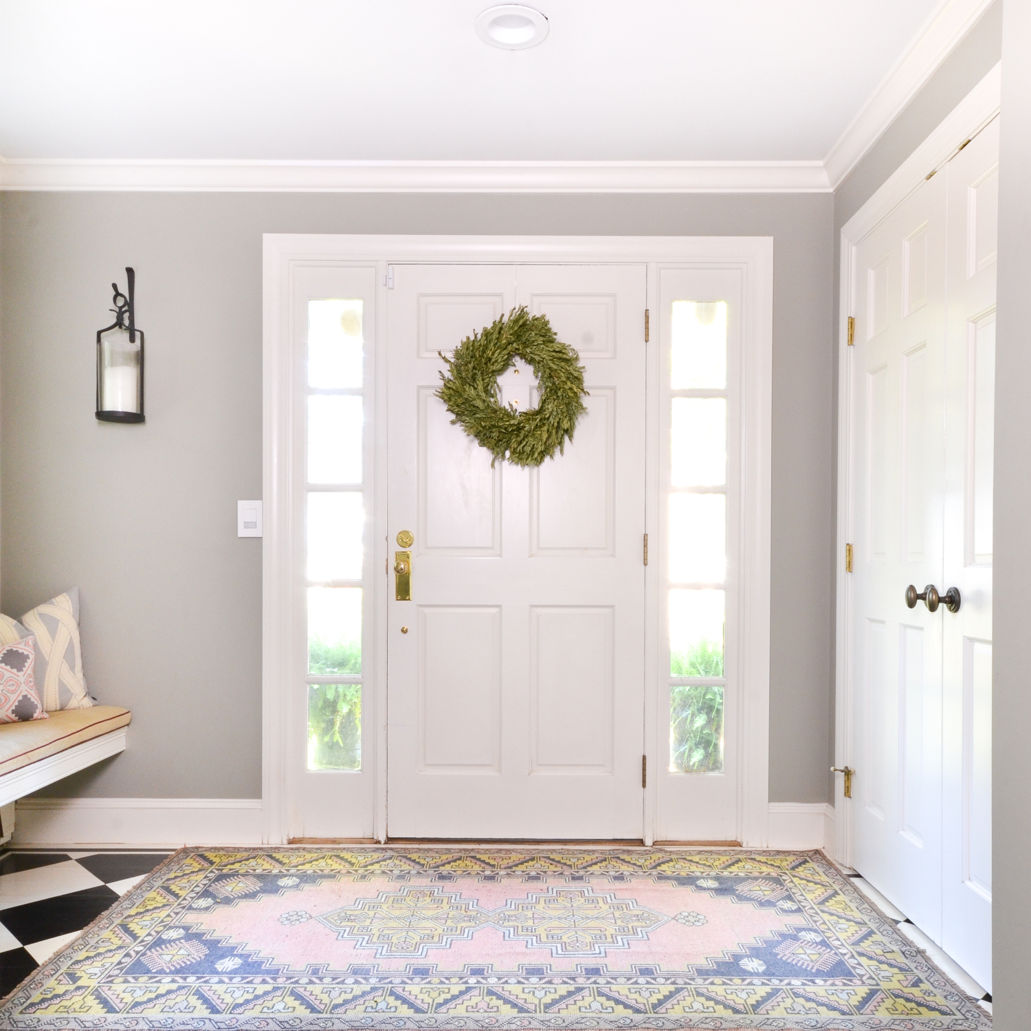 Soft and feminine entryway with vintage rug and brass door hardware