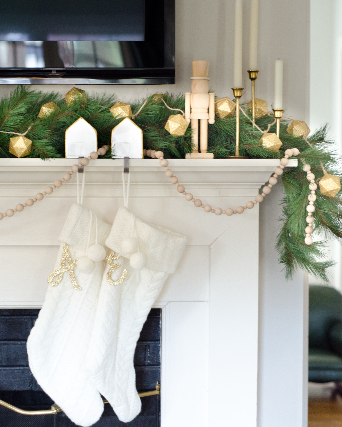 A simple and classic Christmas mantle with greenery, white cable knit stockings, nutcrackers, and gold accents. 2017 Holiday Housewalk