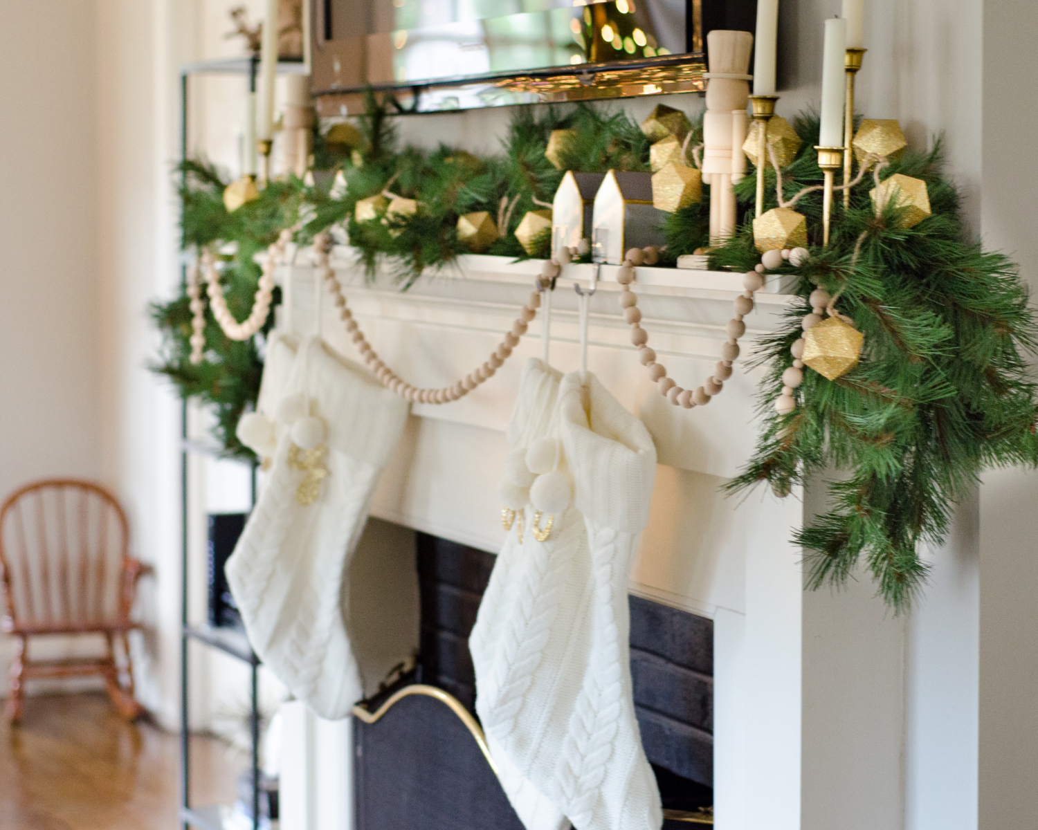 A simple and classic Christmas mantle with greenery, white cable knit stockings, nutcrackers, and gold accents. 2017 Holiday Housewalk