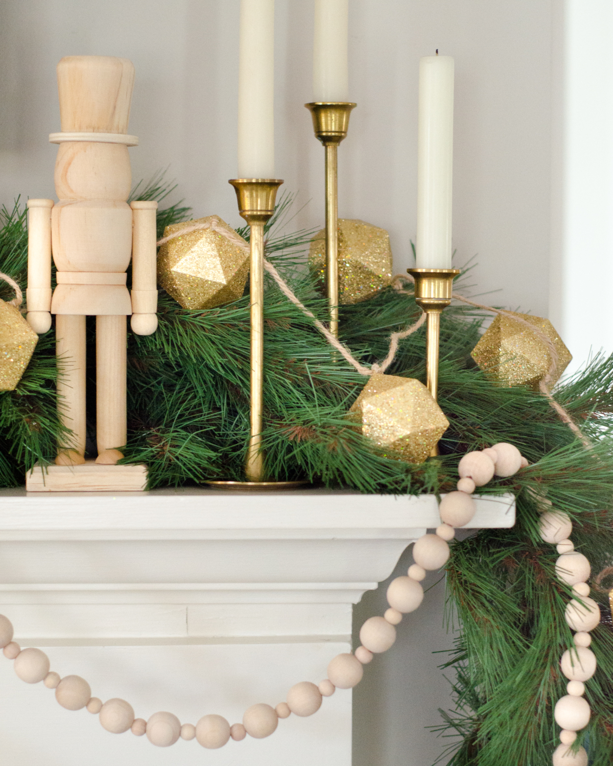 A simple and classic Christmas mantle with greenery, white cable knit stockings, nutcrackers, and gold accents. 2017 Holiday Housewalk