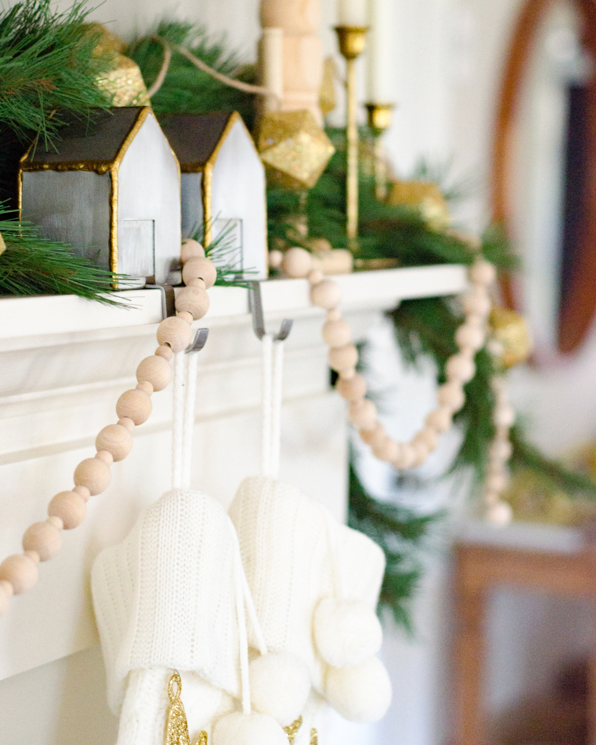 A simple and classic Christmas mantle with greenery, white cable knit stockings, nutcrackers, and gold accents. 2017 Holiday Housewalk