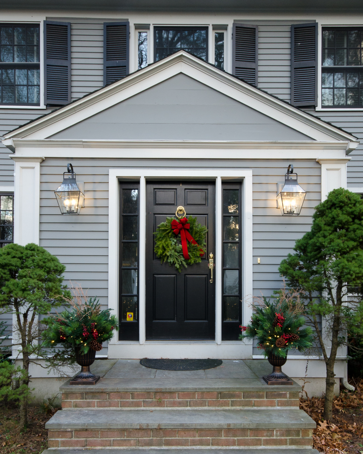 Classic Christmas front door with evergreen wreath and lush urn planters