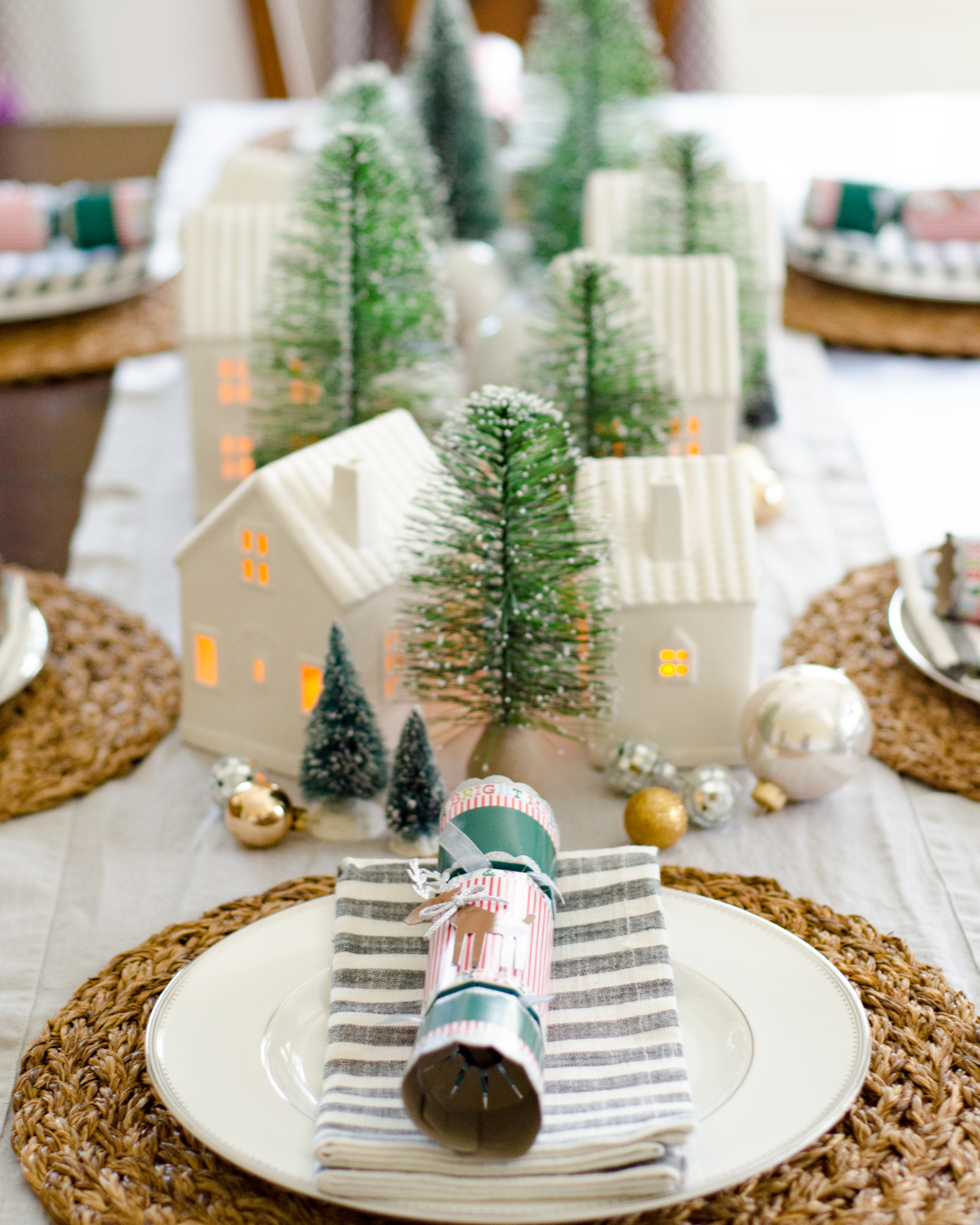 A simple and classic Christmas dining room with ceramic houses and bottle brush trees used as a Christmas centerpiece idea.