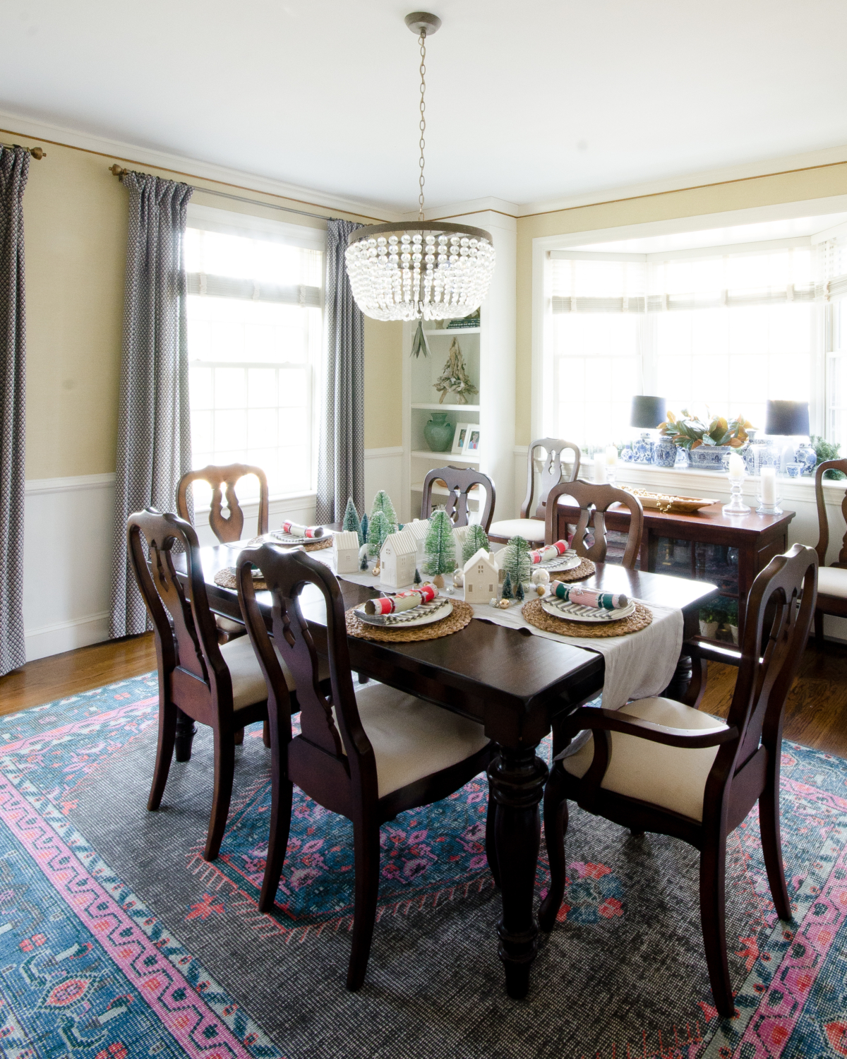 A simple and classic Christmas dining room with ceramic houses and bottle brush trees used as a table centerpiece.