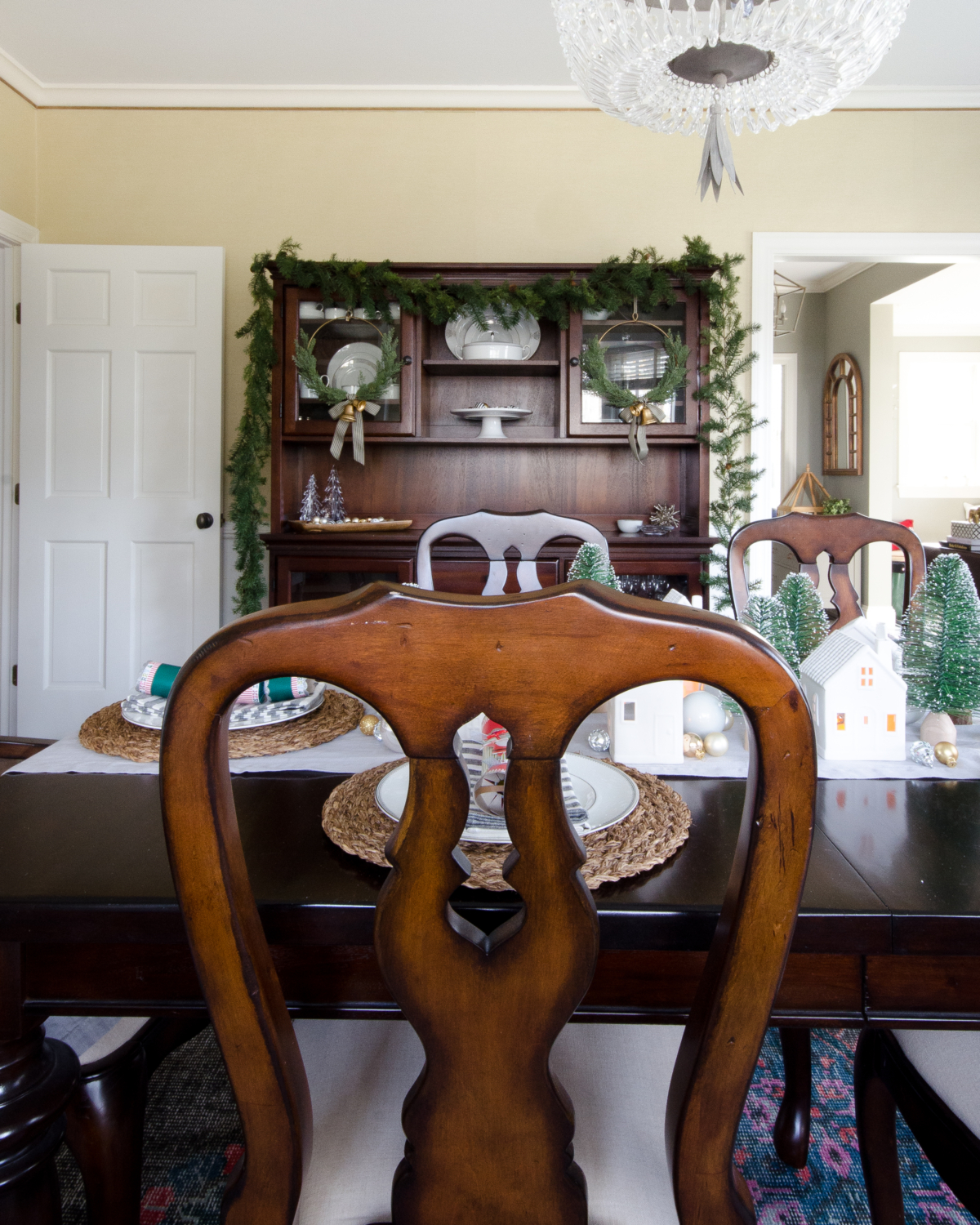 A simple and classic Christmas dining room with ceramic houses and bottle brush trees used as a Christmas centerpiece idea.