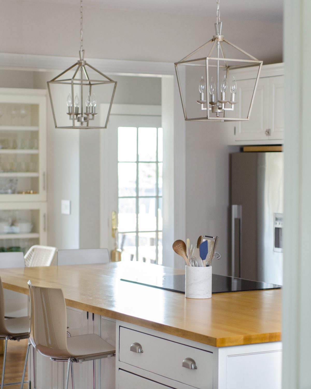 A classic white kitchen with lantern kitchen pendants and warm wood accents. Beautiful mix of traditional and modern in this family-friendly kitchen.